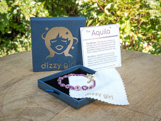 Bracelet in a 'dizzy girl' branded box with a card on a wooden surface.
