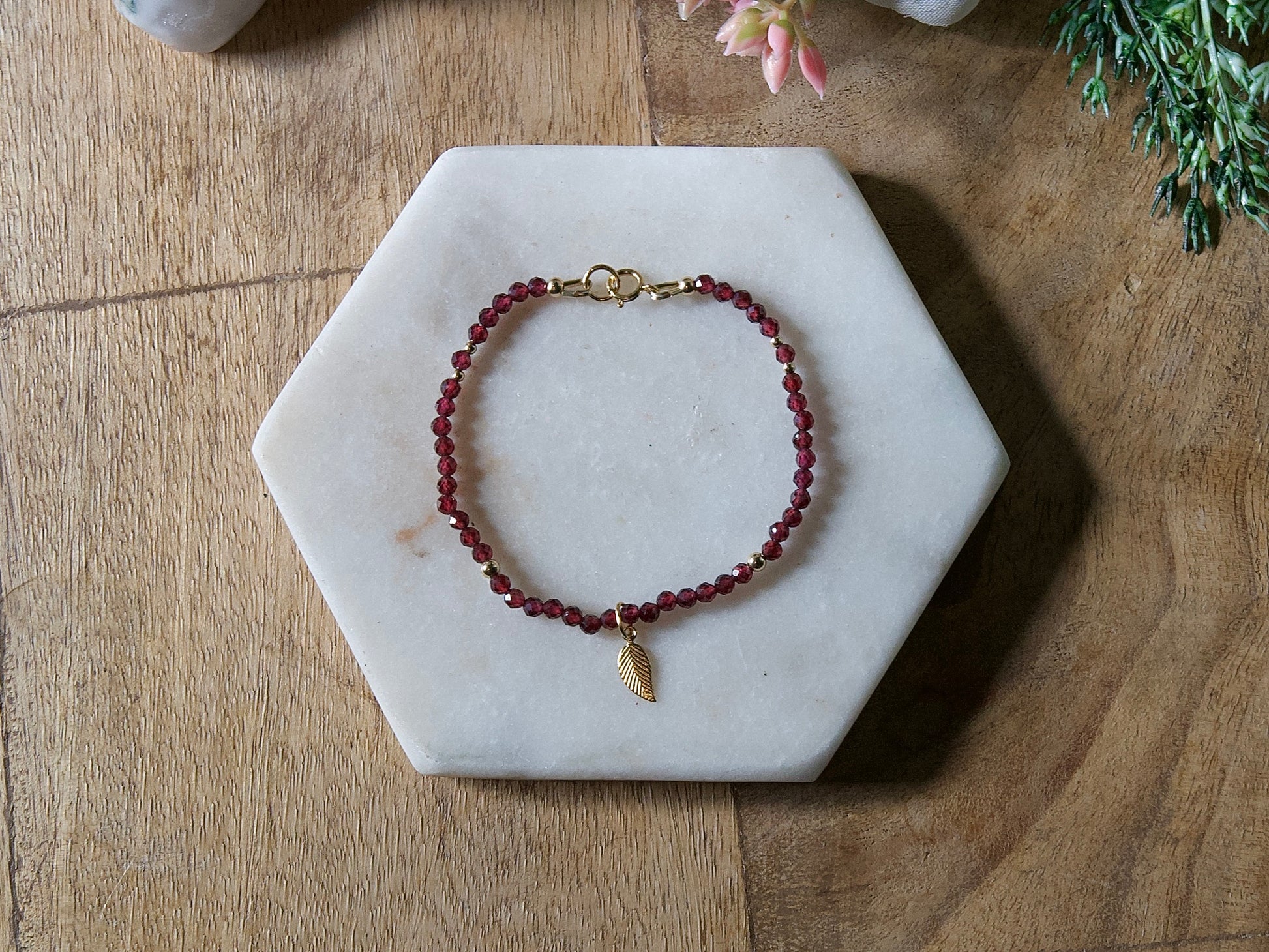 Deep red garnet bracelet with 14k gold-filled leaf-shaped charm and spring ring clasp.