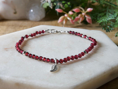 Deep red garnet bracelet with 14k gold-filled leaf-shaped charm and spring ring clasp.