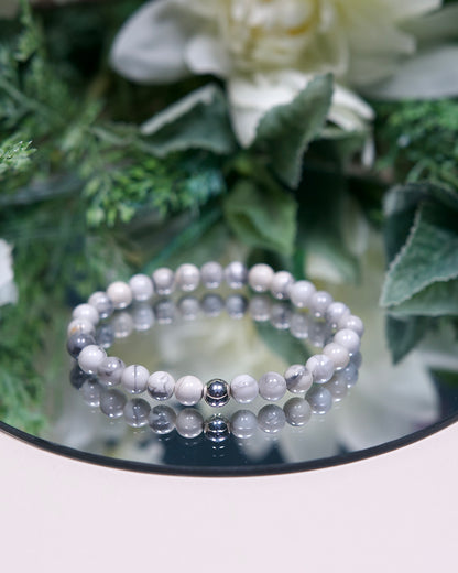 A Howlite beaded gemstone bracelet with white and black marbled beads and a sterling silver accent bead on a mirrored background