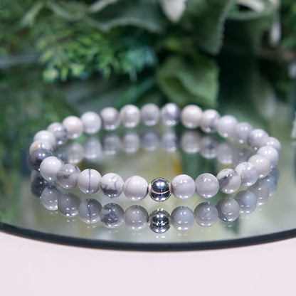 A Howlite beaded gemstone bracelet with white and black marbled beads and a sterling silver accent bead on a mirrored background