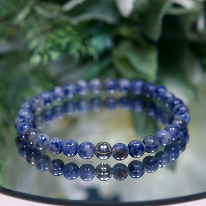 A Blue Spot Jasper beaded gemstone bracelet with mottled dark and pale blue beads and a sterling silver accent bead on a mirrored plate