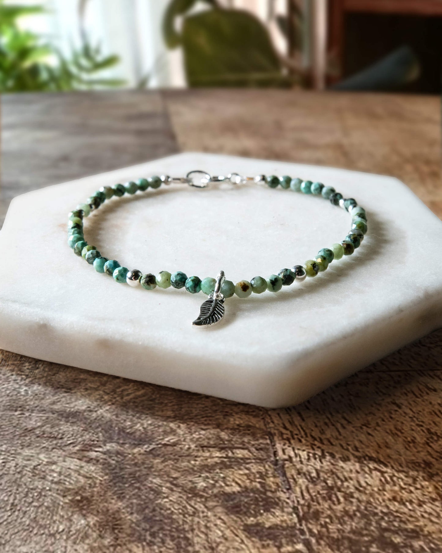 Turquoise and black African turquoise gemstone beaded bracelet with sterling silver leaf-shaped charm and spring ring clasp.