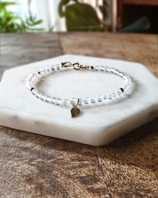 Clear quartz gemstone bracelet with 14k gold-filled leaf-shaped charm and spring ring clasp.