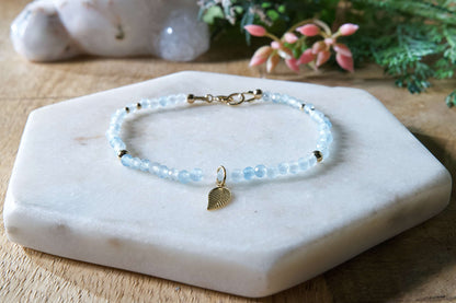 Pale blue aquamarine gemstone beaded bracelet with 14k gold-filled leaf-shaped charm and spring ring closure.