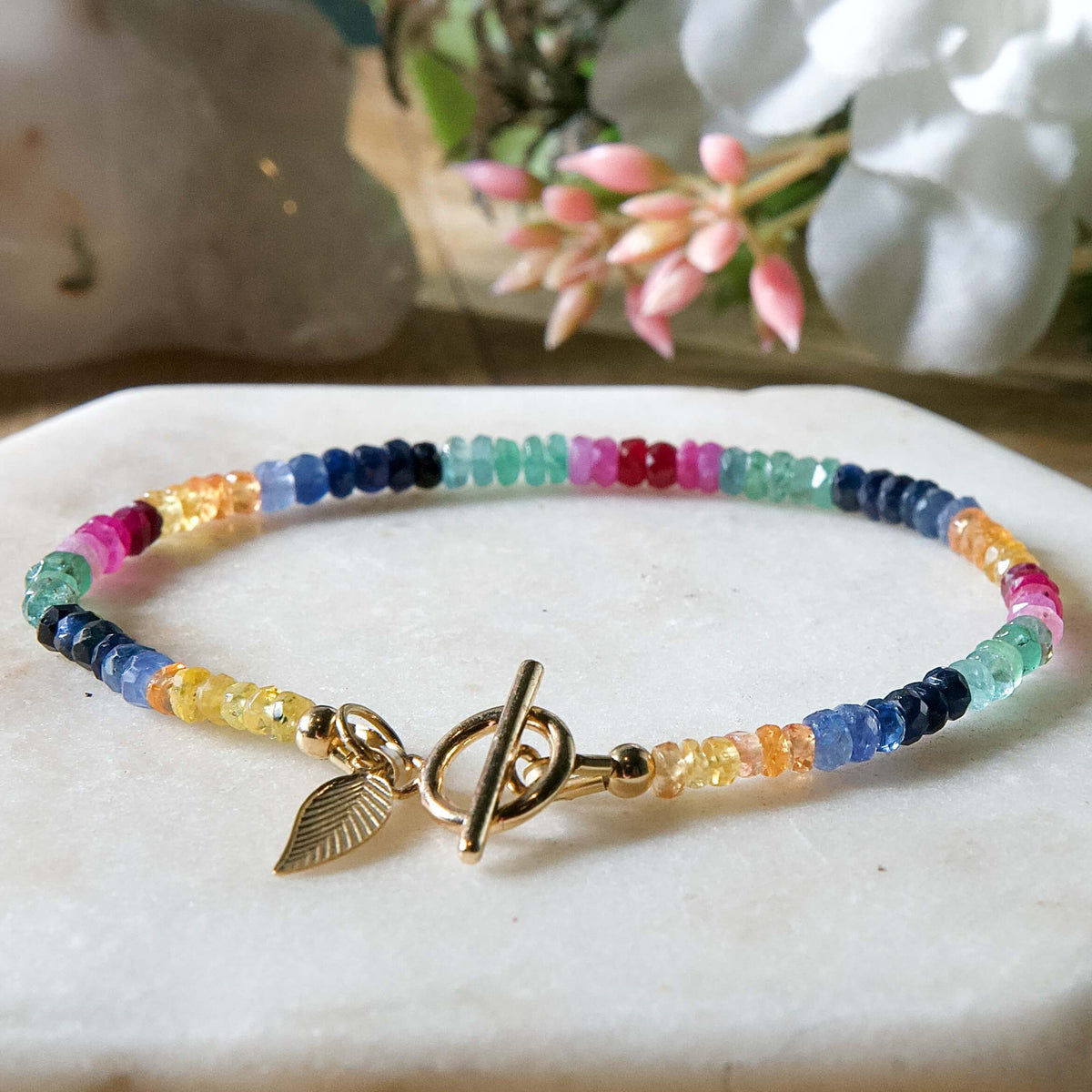 Yellow, blue, green, pink, and red sapphire beaded gemstone bracelet with 14k gold-filled toggle clasp and leaf-shaped charm.