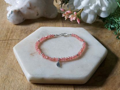 Pink rhodochrosite gemstone beaded bracelet with sterling silver leaf-shaped charm and spring ring clasp.