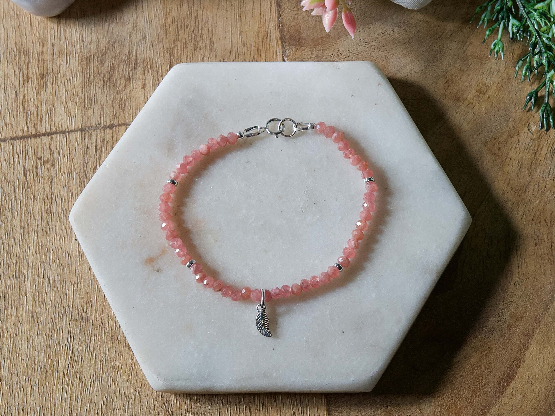 Pink rhodochrosite gemstone beaded bracelet with sterling silver leaf-shaped charm and spring ring clasp.