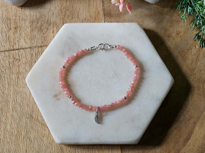 Pink rhodochrosite gemstone beaded bracelet with sterling silver leaf-shaped charm and spring ring clasp.