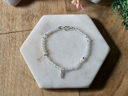 Clear quartz gemstone bracelet with sterling silver leaf-shaped charm and spring ring clasp.