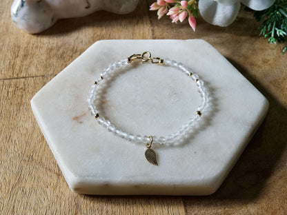 Clear quartz gemstone bracelet with 14k gold-filled leaf-shaped charm and spring ring clasp.