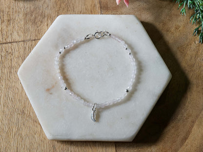 Pale pink rose quartz gemstone beaded bracelet with sterling silver leaf-shaped charm and spring ring closure.