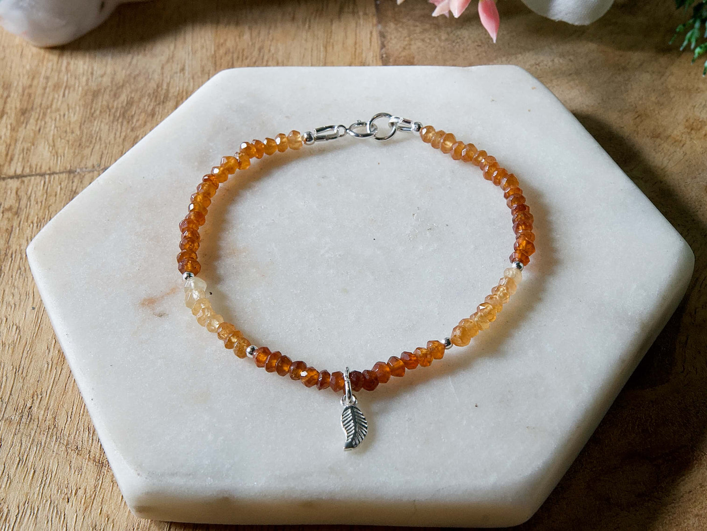 Orange and yellow Hessonite garnet gemstone beaded bracelet with sterling silver leaf-shaped charm and spring ring clasp.