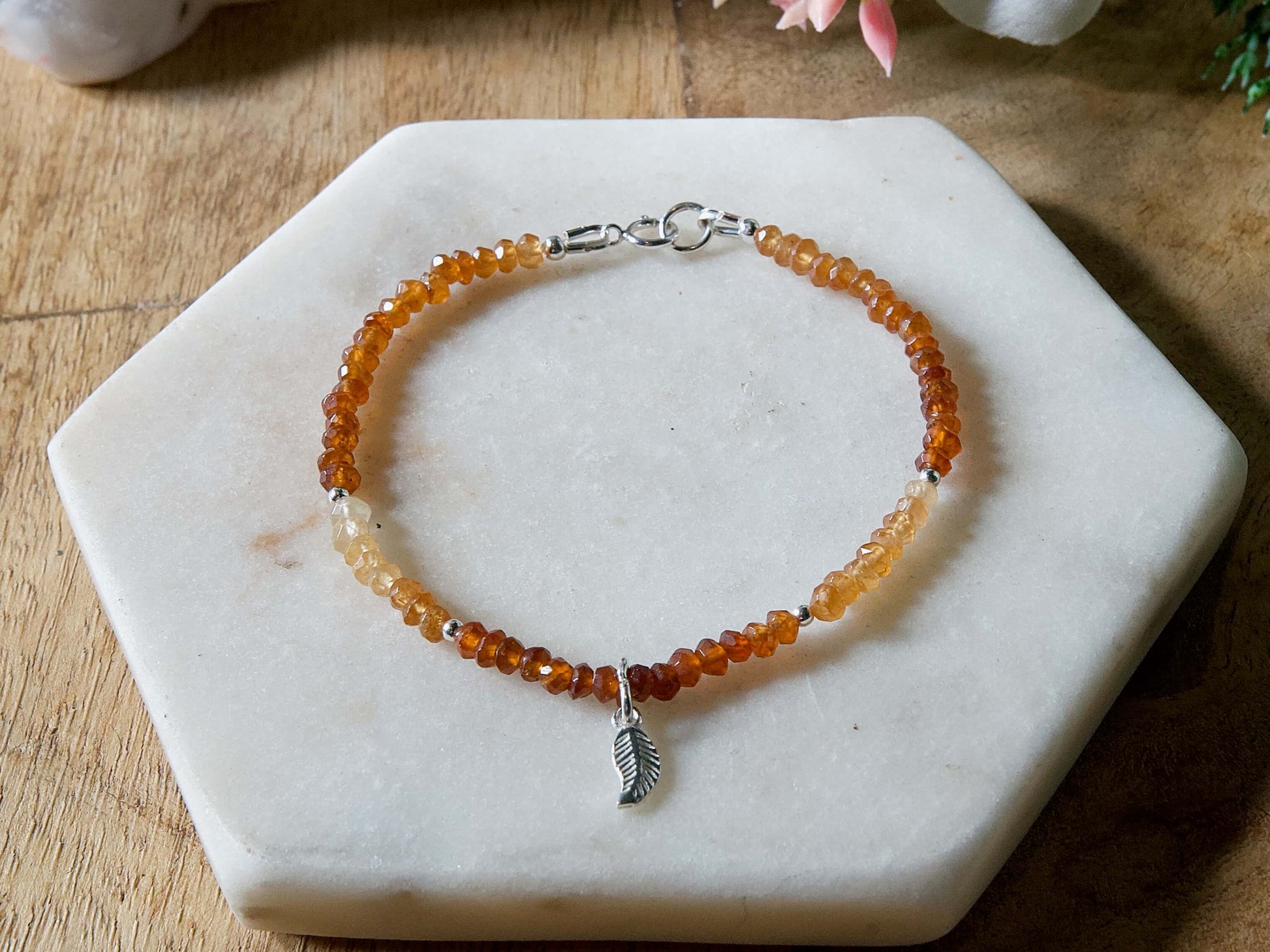 Orange and yellow Hessonite garnet gemstone beaded bracelet with sterling silver leaf-shaped charm and spring ring clasp.