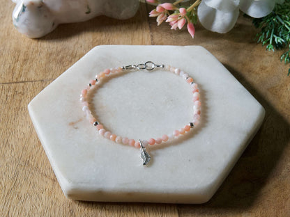 Pale pink opal gemstone beaded bracelet with sterling silver leaf-shaped charm and spring ring clasp.