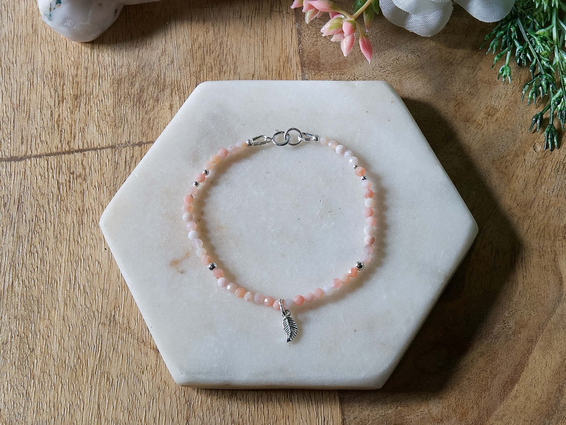 Pale pink opal gemstone beaded bracelet with sterling silver leaf-shaped charm and spring ring clasp.
