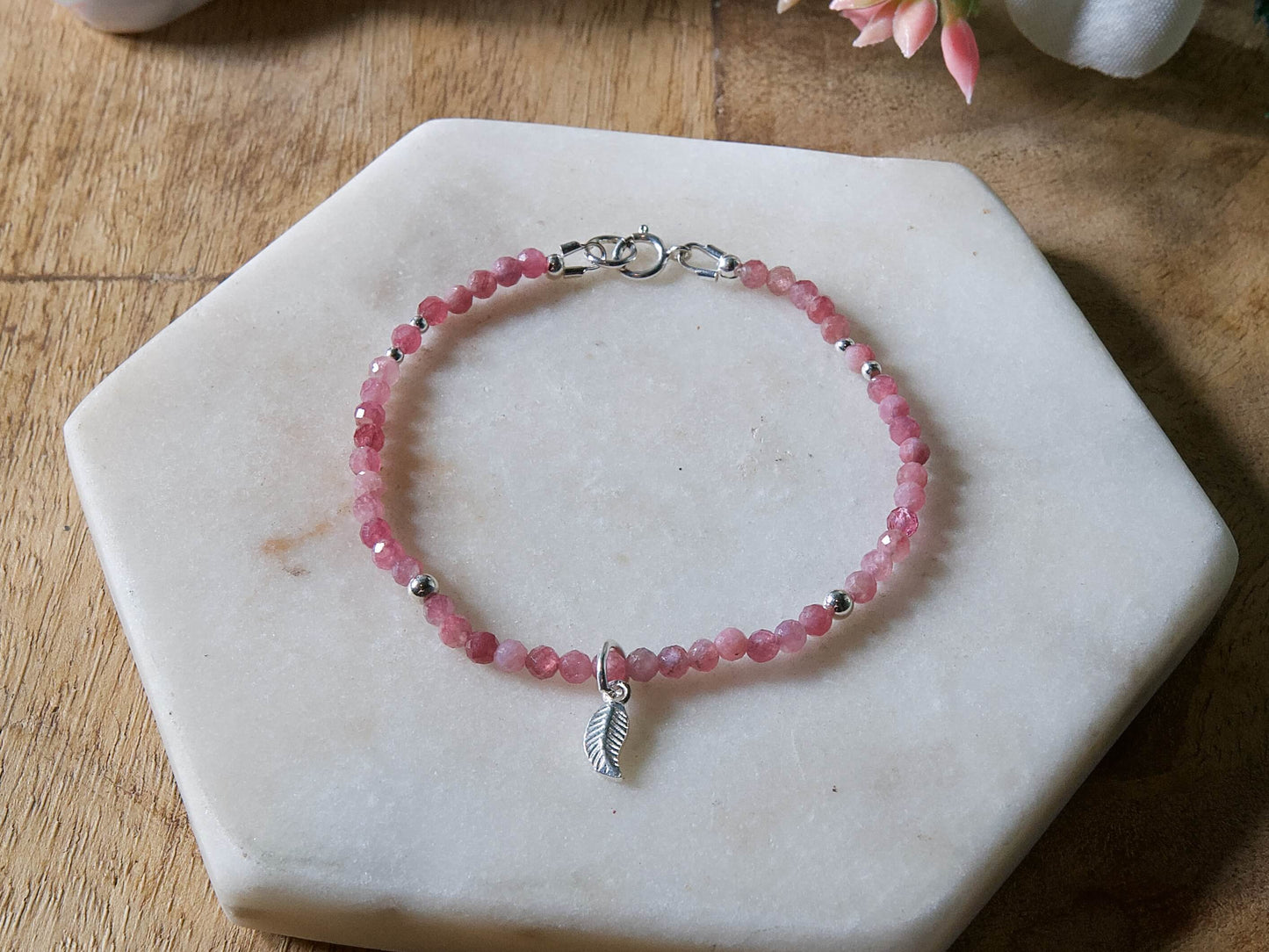 Pink tourmaline gemstone beaded bracelet with sterling silver leaf-shaped charm and spring ring closure.