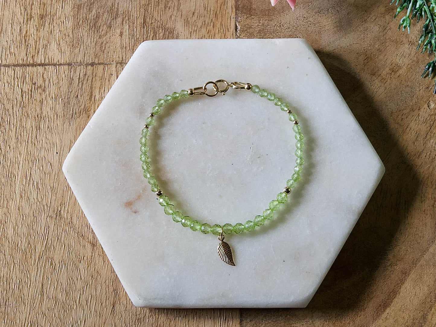 Green peridot gemstone beaded bracelet with 14k gold-filled leaf-shaped charm and spring ring closure.