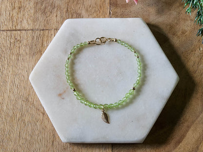 Green peridot gemstone beaded bracelet with 14k gold-filled leaf-shaped charm and spring ring closure.