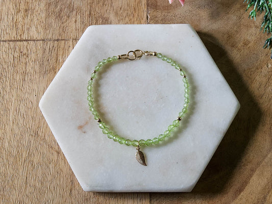 Green peridot gemstone beaded bracelet with 14k gold-filled leaf-shaped charm and spring ring closure.