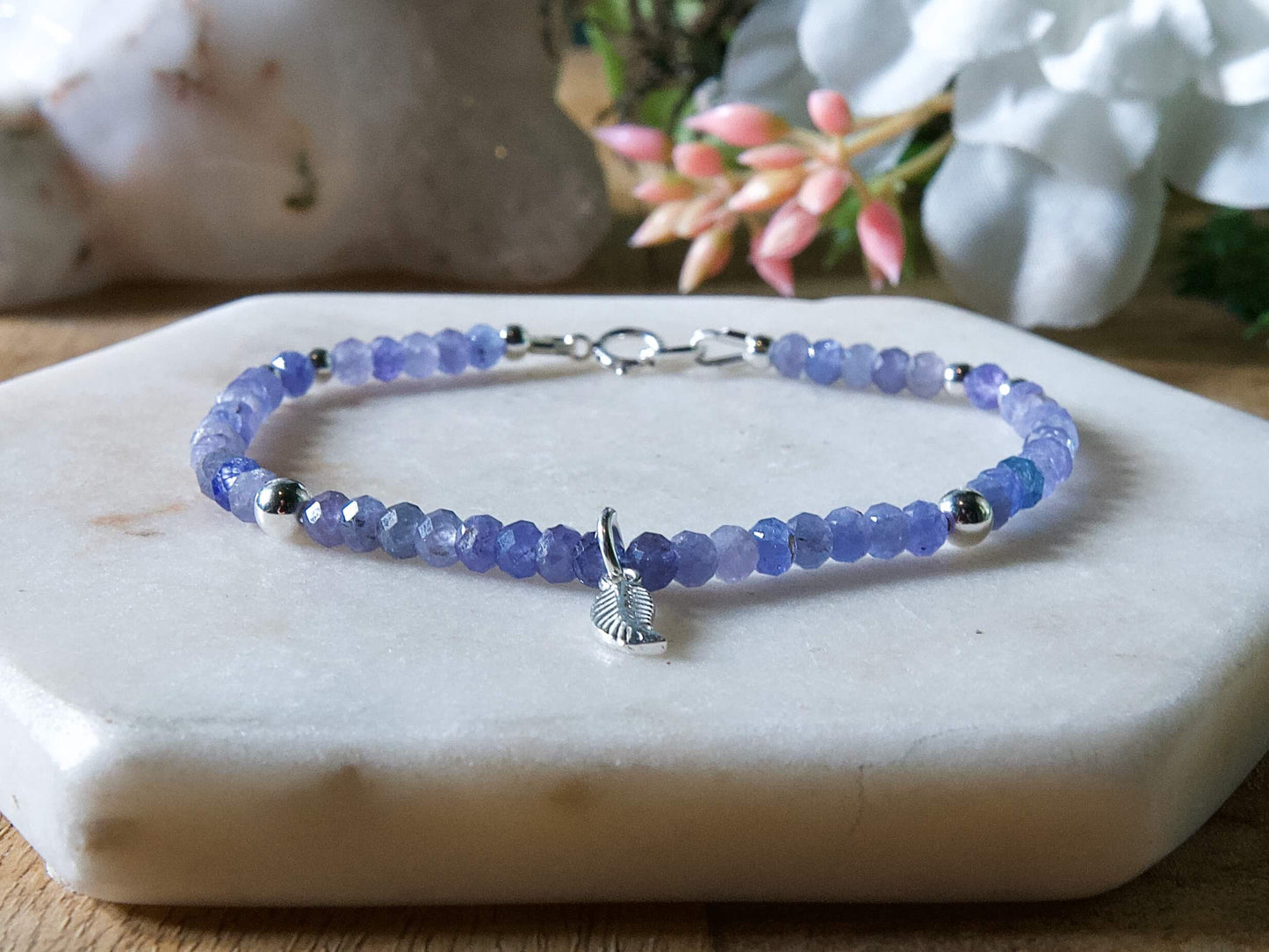 Periwinkle blue tanzanite gemstone beaded bracelet with sterling silver leaf-shaped charm and spring ring clasp.