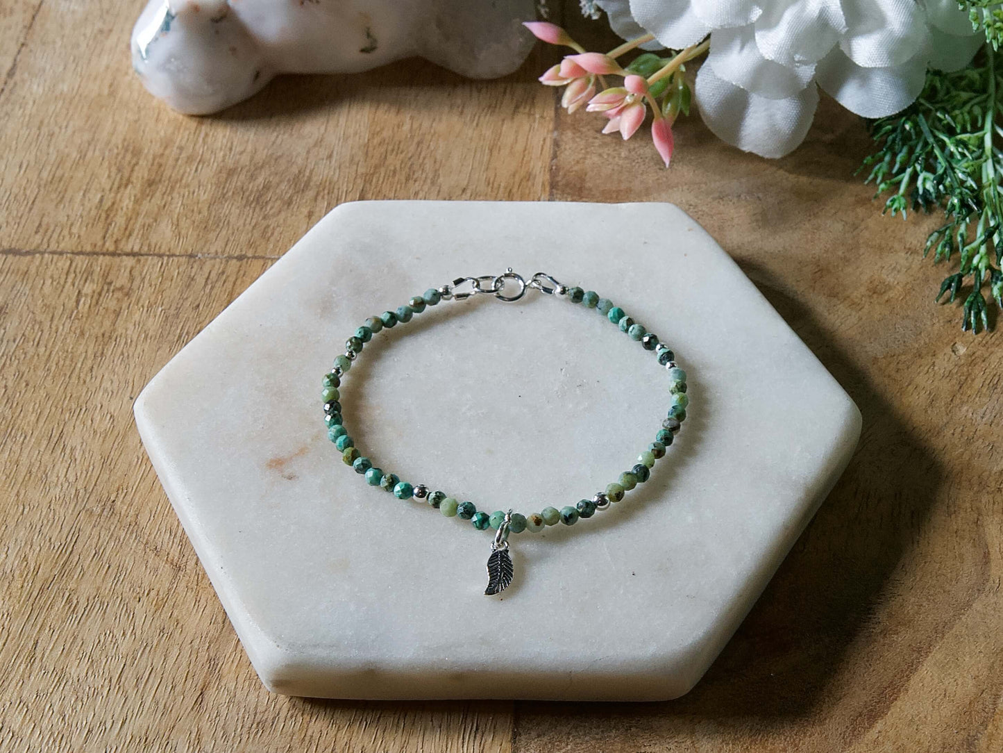 Turquoise and black African turquoise gemstone beaded bracelet with sterling silver leaf-shaped charm and spring ring clasp.
