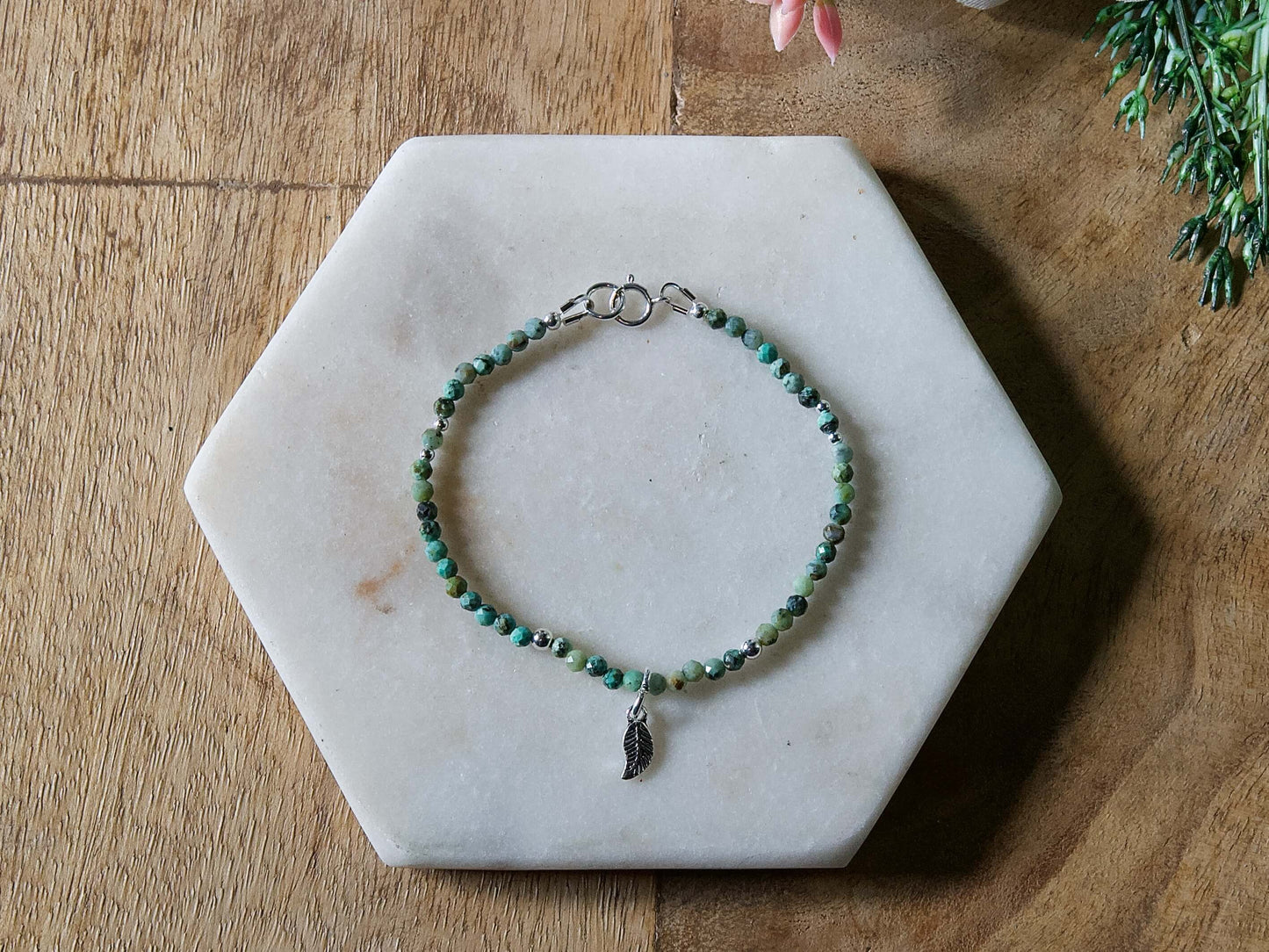 Turquoise and black African turquoise gemstone beaded bracelet with sterling silver leaf-shaped charm and spring ring clasp.