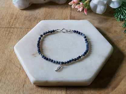 Deep blue sapphire gemstone beaded bracelet with sterling silver leaf-shaped charm and spring ring closure.