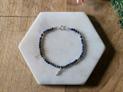 Deep blue sapphire gemstone beaded bracelet with sterling silver leaf-shaped charm and spring ring closure.