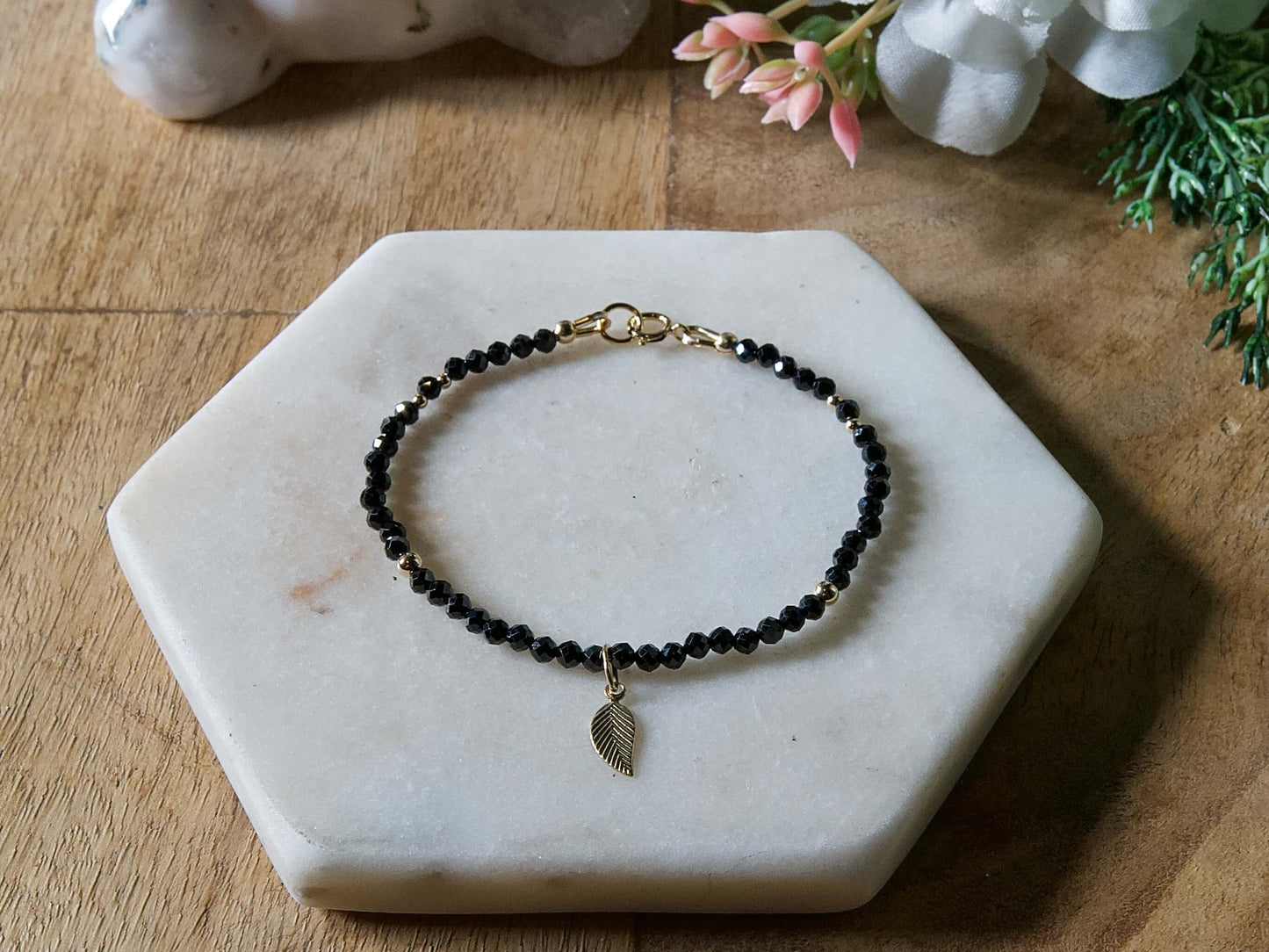 Black onyx gemstone beaded bracelet with 14k gold-filled leaf-shaped charm and spring ring closure.