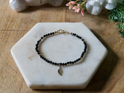 Black onyx gemstone beaded bracelet with 14k gold-filled leaf-shaped charm and spring ring closure.