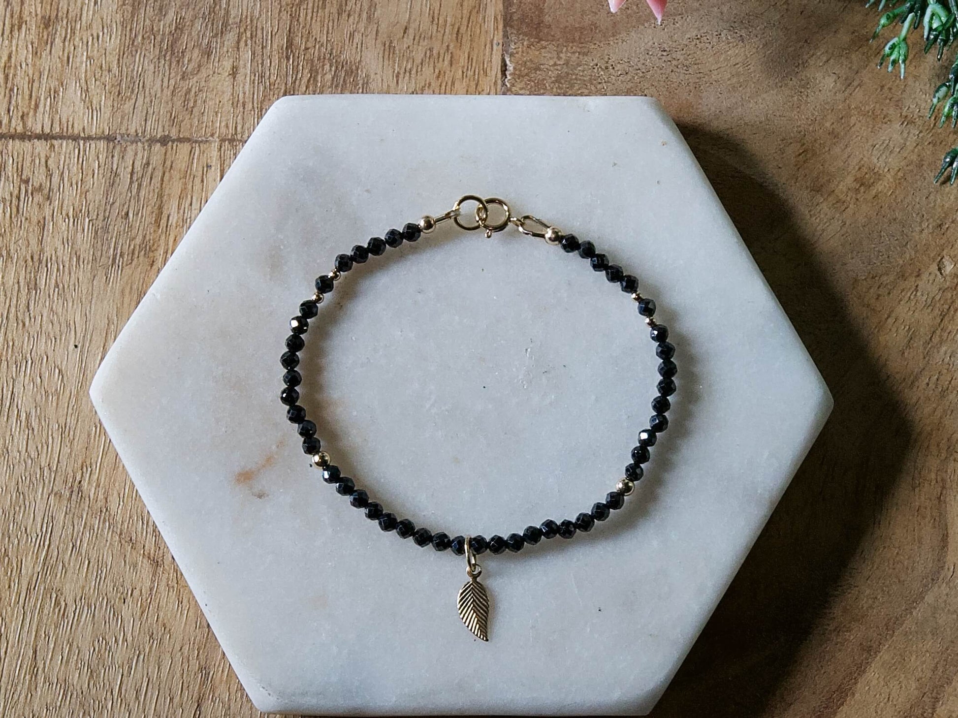 Black spinel gemstone beaded bracelet with 14k gold-filled leaf-shaped charm and spring ring clasp.