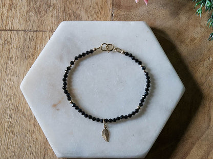 Black spinel gemstone beaded bracelet with 14k gold-filled leaf-shaped charm and spring ring clasp.