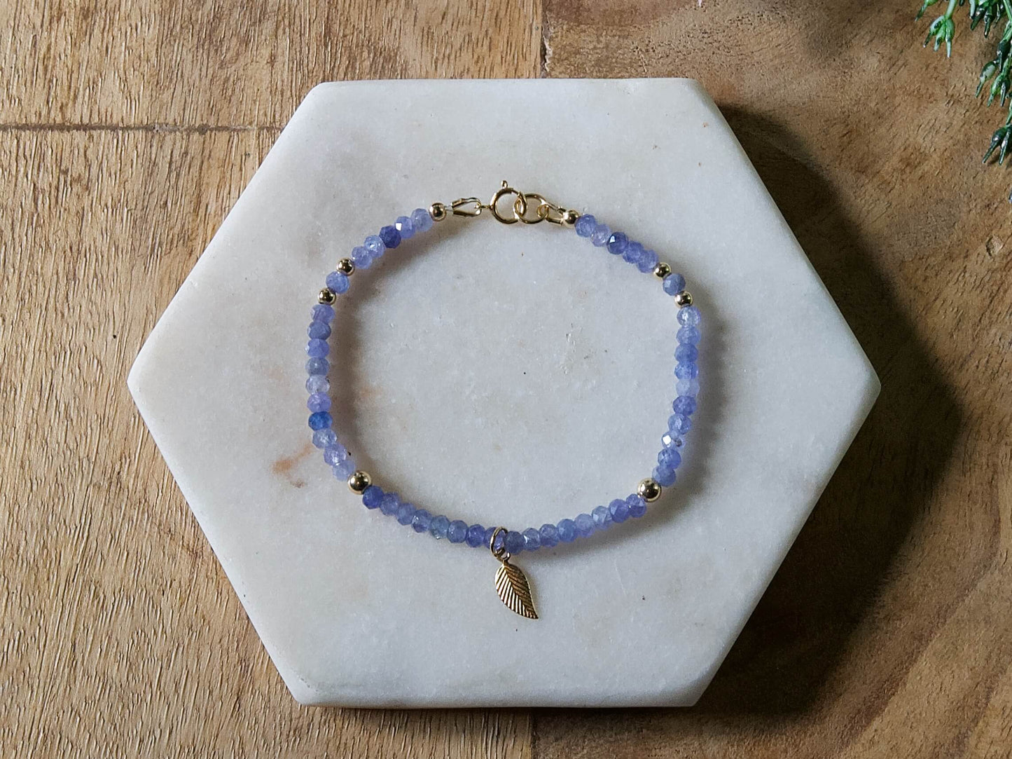 Periwinkle blue tanzanite gemstone beaded bracelet with 14k gold-filled leaf-shaped charm and spring ring clasp.