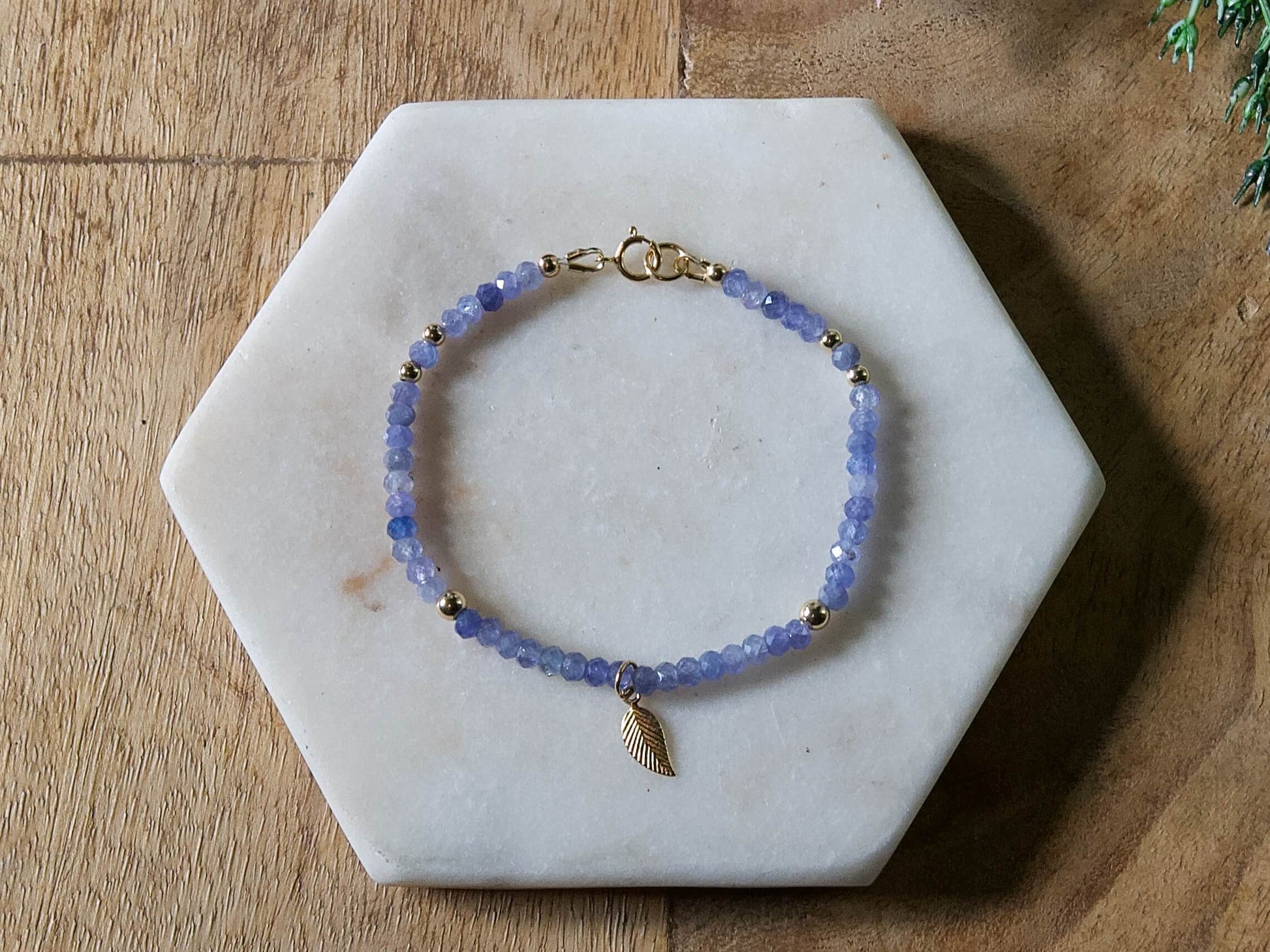 Periwinkle blue tanzanite gemstone beaded bracelet with 14k gold-filled leaf-shaped charm and spring ring clasp.