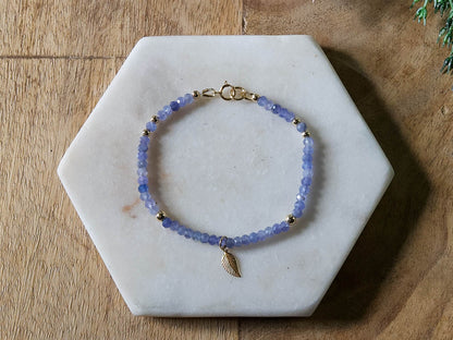Periwinkle blue tanzanite gemstone beaded bracelet with 14k gold-filled leaf-shaped charm and spring ring clasp.