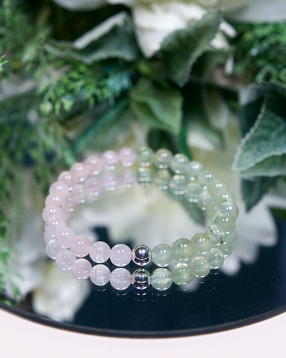 Pale pink Madagascar Rose Quartz and pale green Prehnite beaded gemstone bracelet with smooth round beads and a sterling silver accent bead on a mirrored background