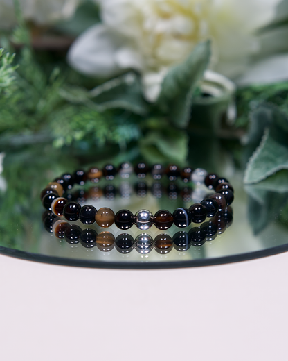 Dark brown solid and banded round Botswana Agate beads with sterling silver accent bead on mirrored plate