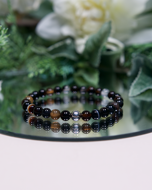 Dark brown solid and banded round Botswana Agate beads with sterling silver accent bead on mirrored plate