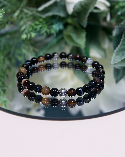 Dark brown solid and banded round Botswana Agate beads with sterling silver accent bead on mirrored plate