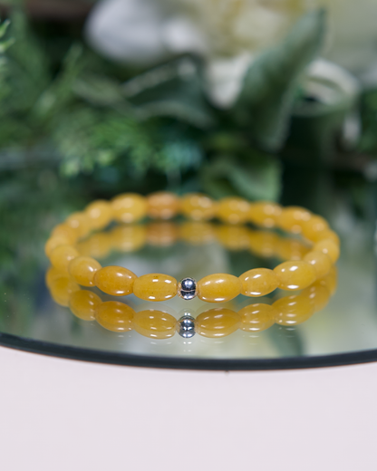 Yellow Aventurine barrel-shaped beaded bracelet with sterling silver accent bead on mirrored plate