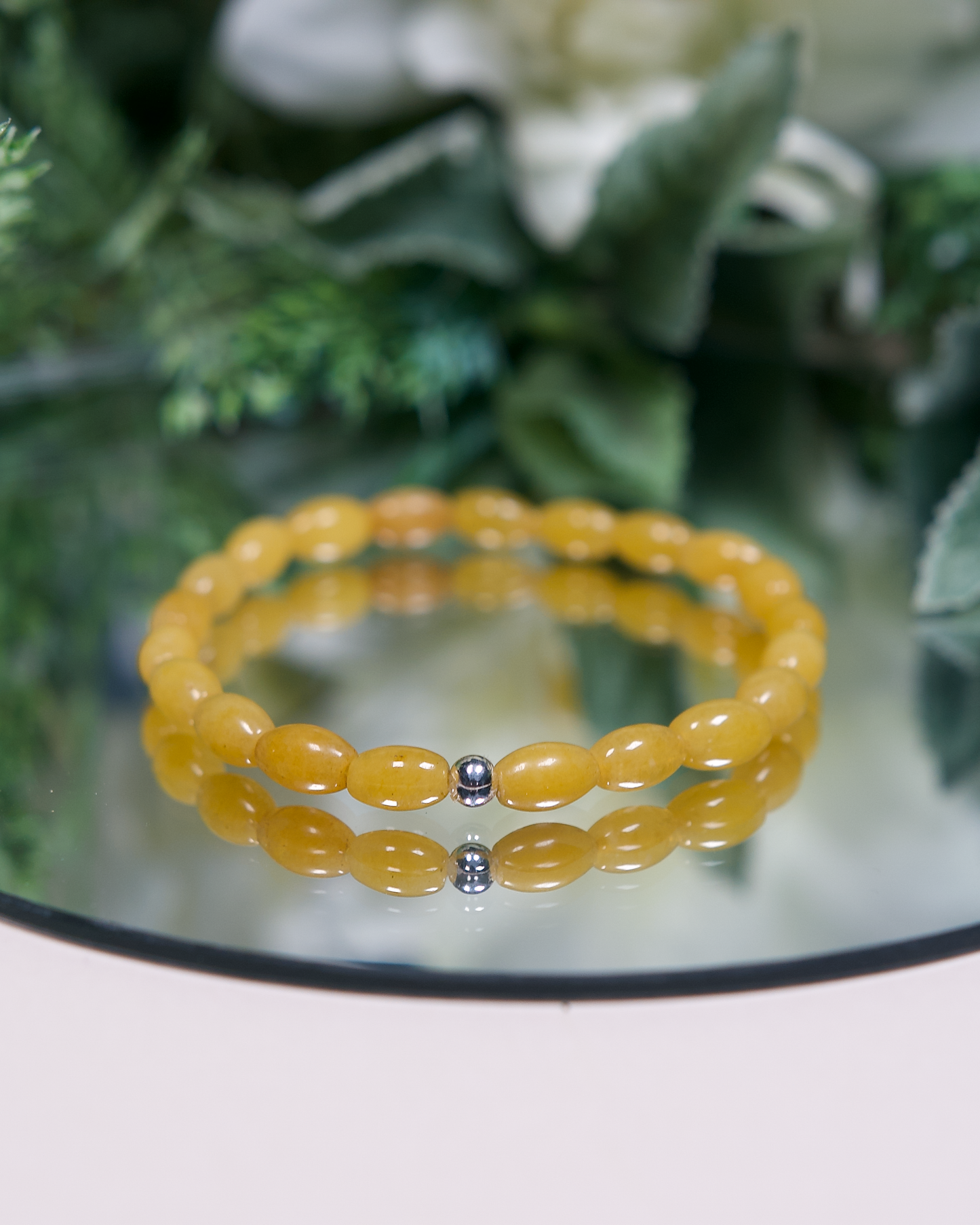 Close up of a yellow aventurine bracelet with barrel-shaped beads and a sterling silver accent bead.