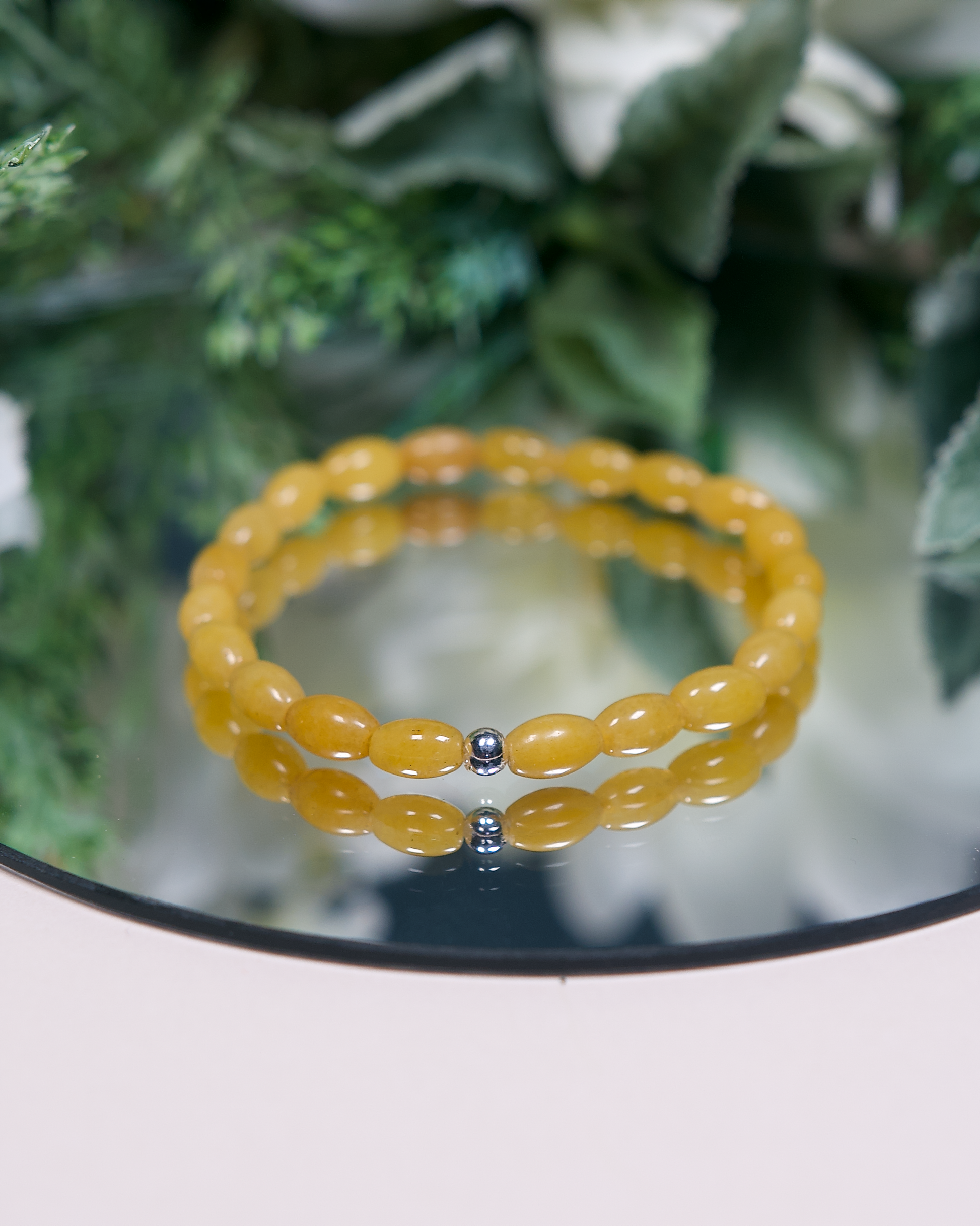 Close up of a yellow aventurine bracelet with barrel-shaped beads and a sterling silver accent bead.