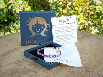 Bracelet in a 'dizzy girl' branded box with a care card on a wooden surface.