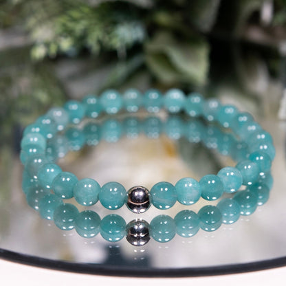 A turquoise Peruvian Amazonite beaded gemstone bracelet with smooth round beads and a sterling silver accent bead on a mirrored plate
