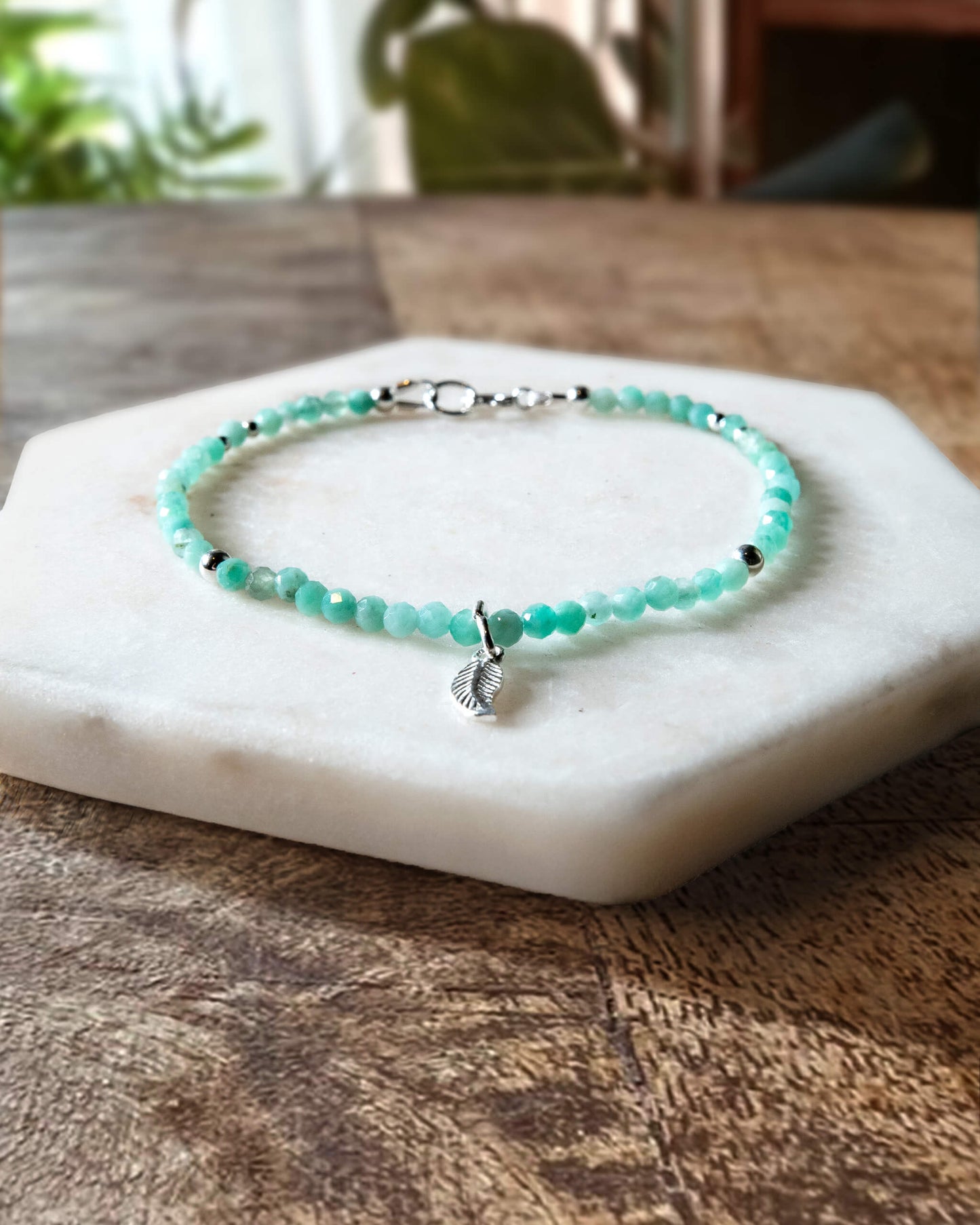 Green emerald gemstone beaded bracelet with sterling silver leaf-shaped charm and spring ring closure.