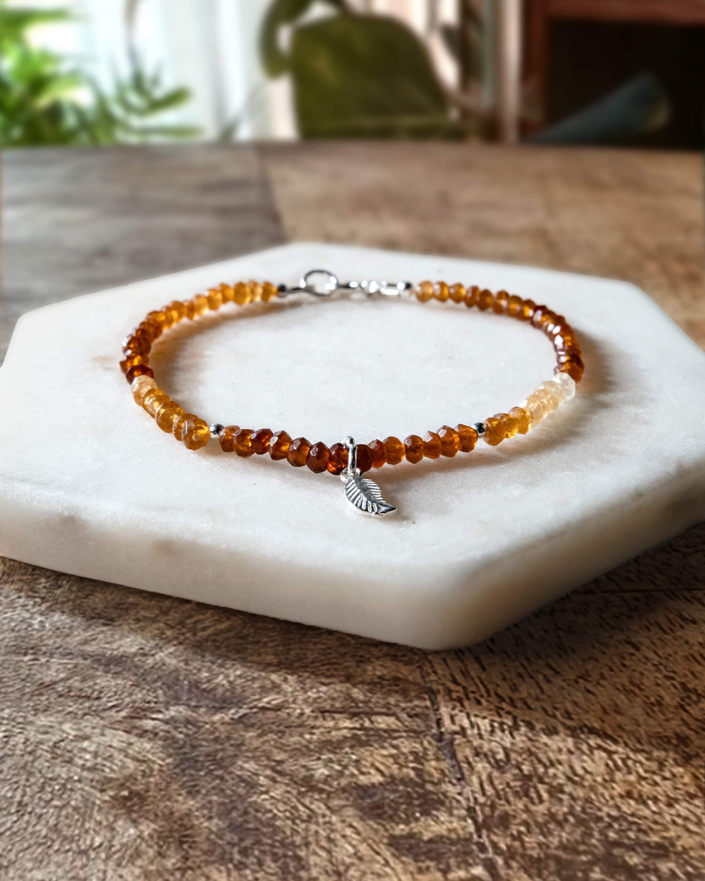 Orange and yellow Hessonite garnet gemstone beaded bracelet with sterling silver leaf-shaped charm and spring ring clasp.