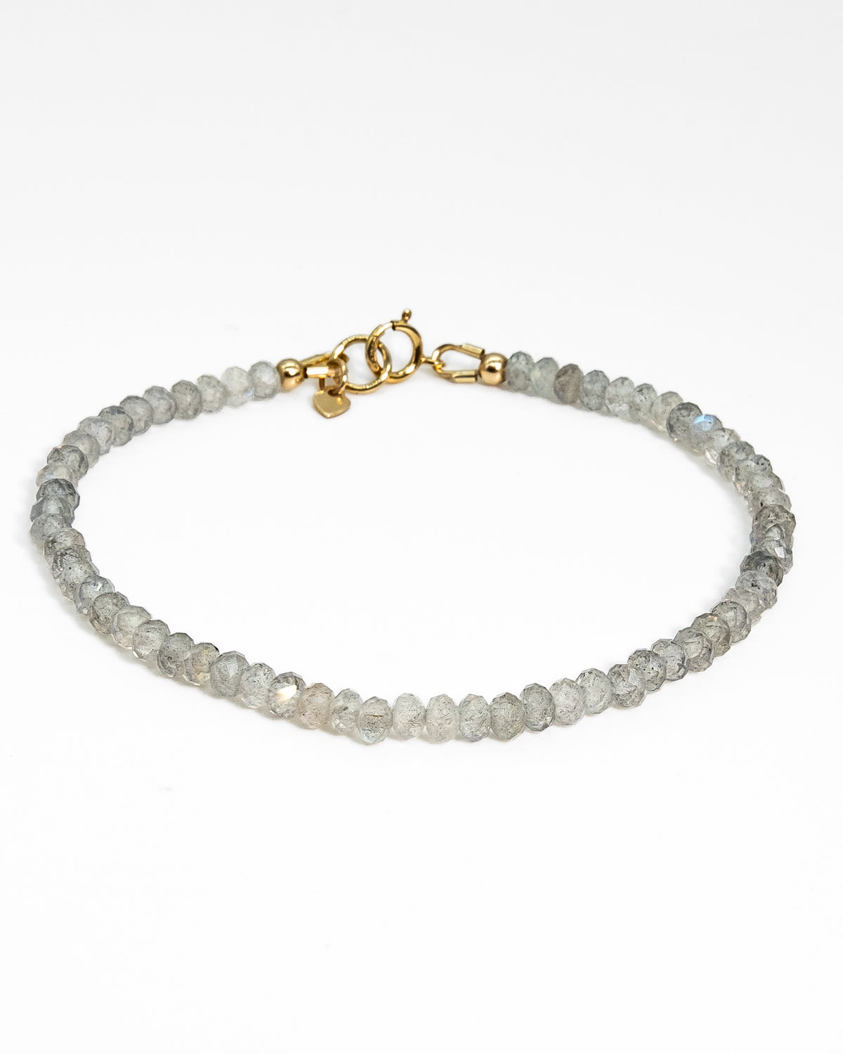 Grey with blue flash Labradorite faceted beaded bracelet stacked on wrist with 14k gold-filled beaded bracelet and 14k gold-filled paperclip chain on wood table