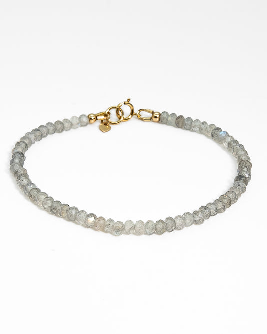 Grey with blue flash Labradorite faceted beaded bracelet stacked on wrist with 14k gold-filled beaded bracelet and 14k gold-filled paperclip chain on wood table