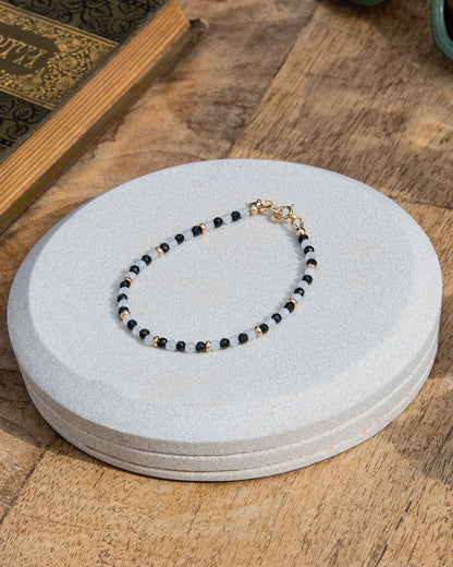 Handcrafted dainty black onyx and white moonstone beaded gemstone bracelet with 14k gold-filled beads, small heart charm, and spring ring clasp. 